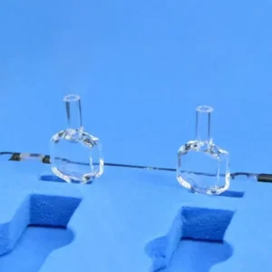 A pair of 10mm pathlength quartz fluorescence flow cells positioned side-by-side on a dark, reflective surface, emphasizing their identical, precise construction.