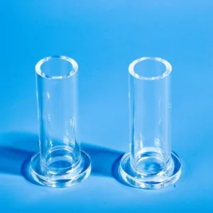 Two transparent single end quartz tubes with integrated circular flanges at their base, standing upright on a vibrant blue background.
