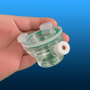 A hand holding a smaller, transparent quartz reaction vessel component of a photocatalytic reactor, highlighting its intricate design and smooth surfaces.