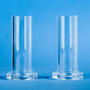 A pair of single end quartz tubes with flanges, displayed against a blue background, highlighting their clear, cylindrical form and sturdy base.